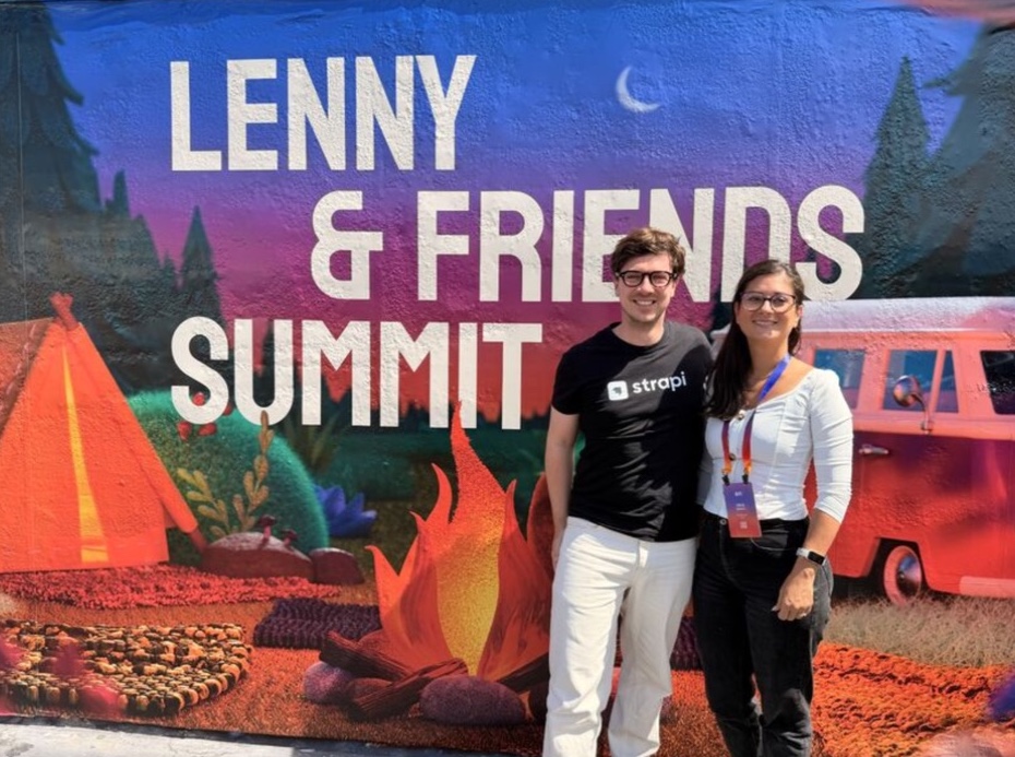 Two attendees together in front of the Summit mural