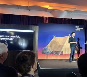 A workshop speaker beside a projected tent illustration