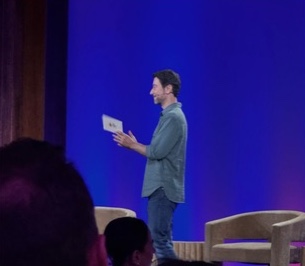 A speaker sharing a thought on the blue-lit stage